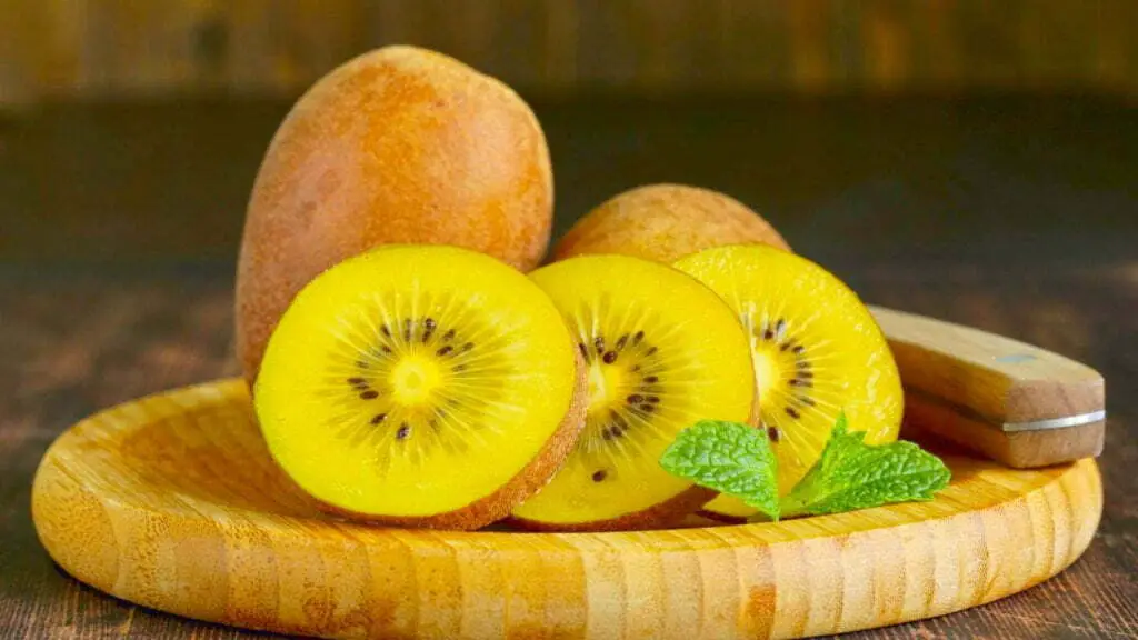 Kiwi fruit and kiwi slices on a wooden plate
